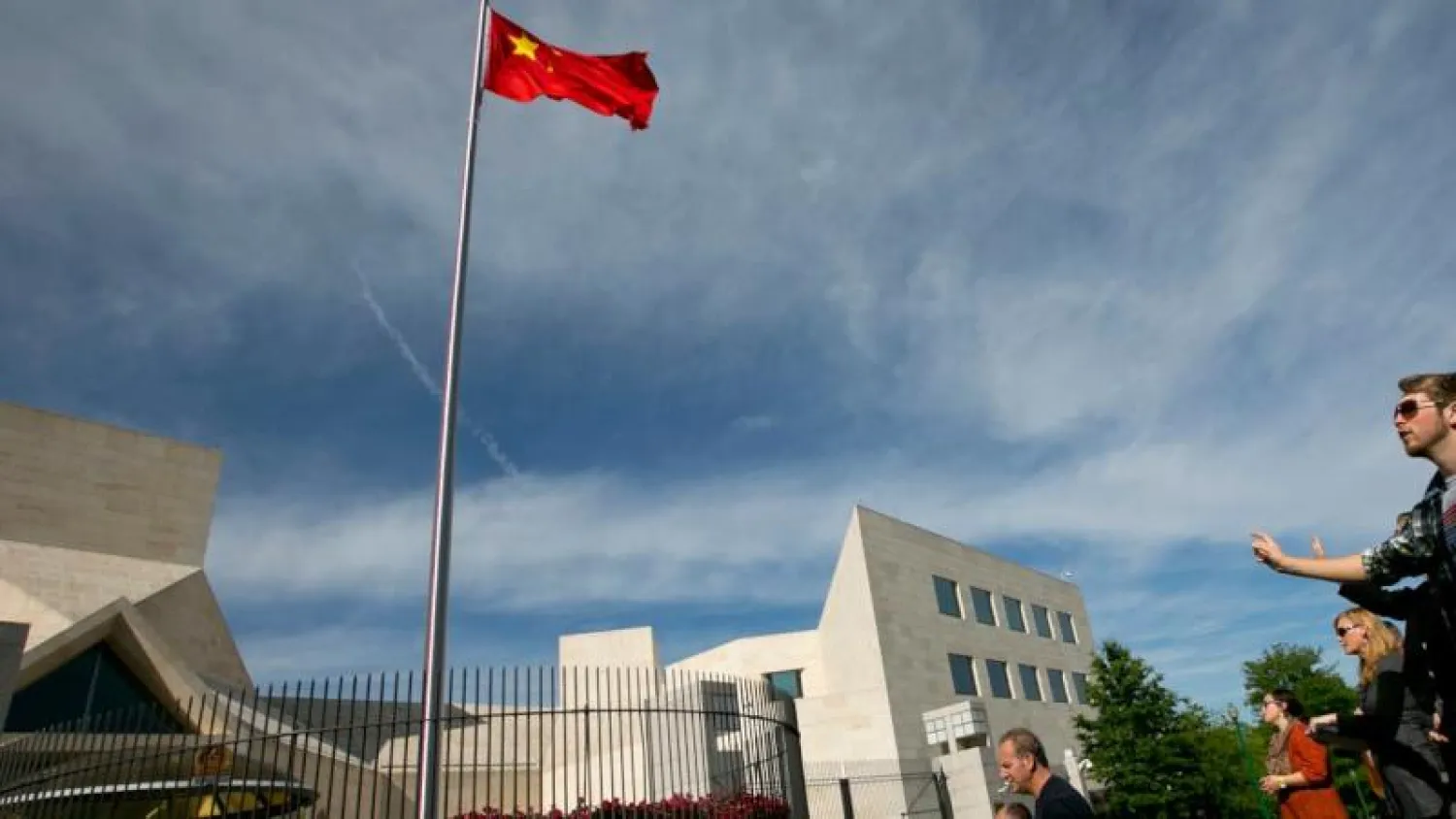 أشخاص يقفون خارج مقر السفارة الصينية في واشنطن (رويترز)