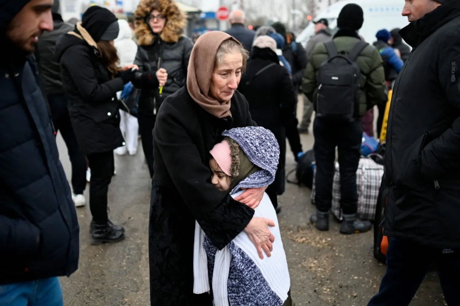 A woman hugs a girl as refugees from Ukraine wait for transport at the Moldova-Ukrainian border checkpoint near the town of Palanca on March 1, 2022. (AFP Photo)