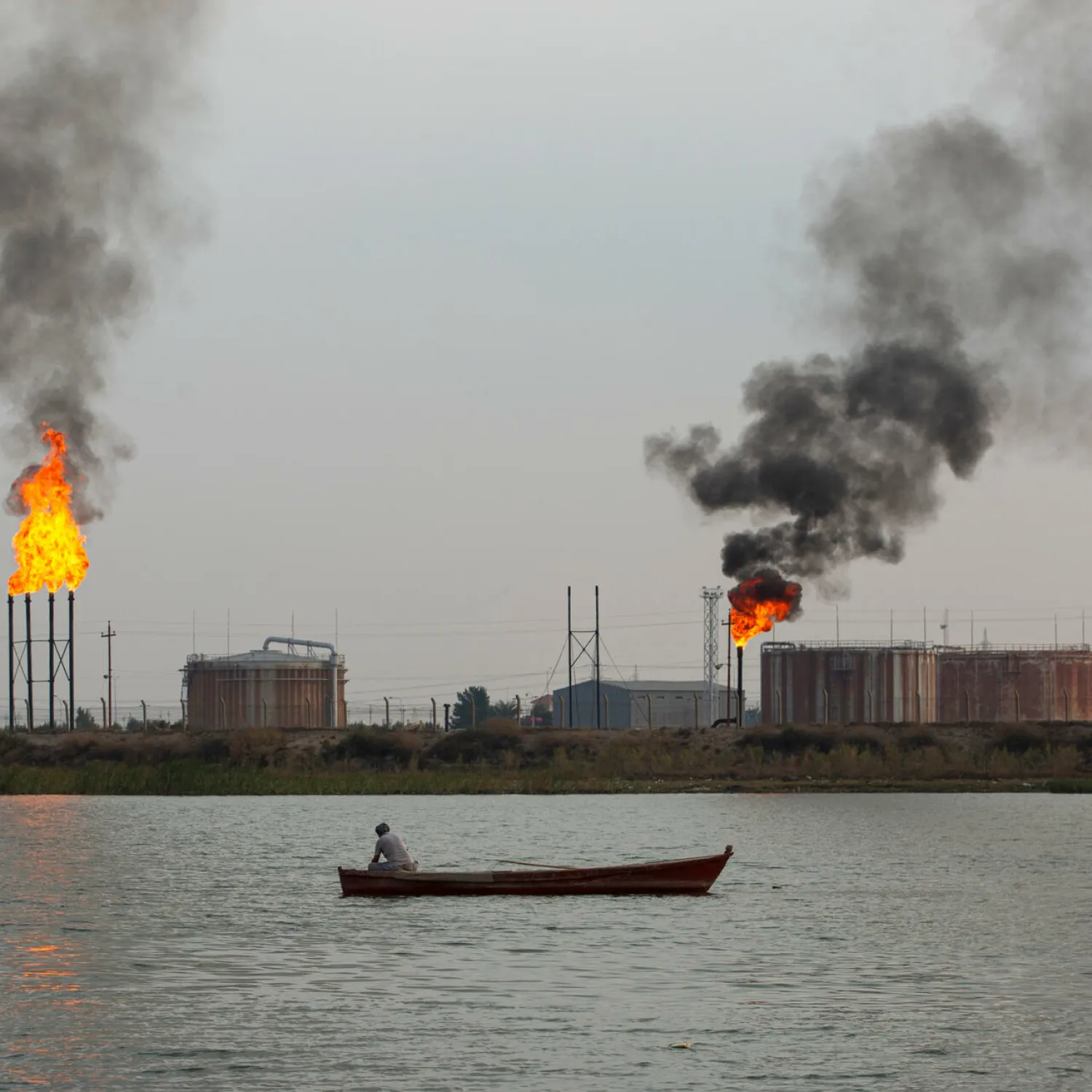 A boat passes polluting gas flares at the Umm Qasr port near Iraq's southern city of Basra. Hussein FALEH AFP
