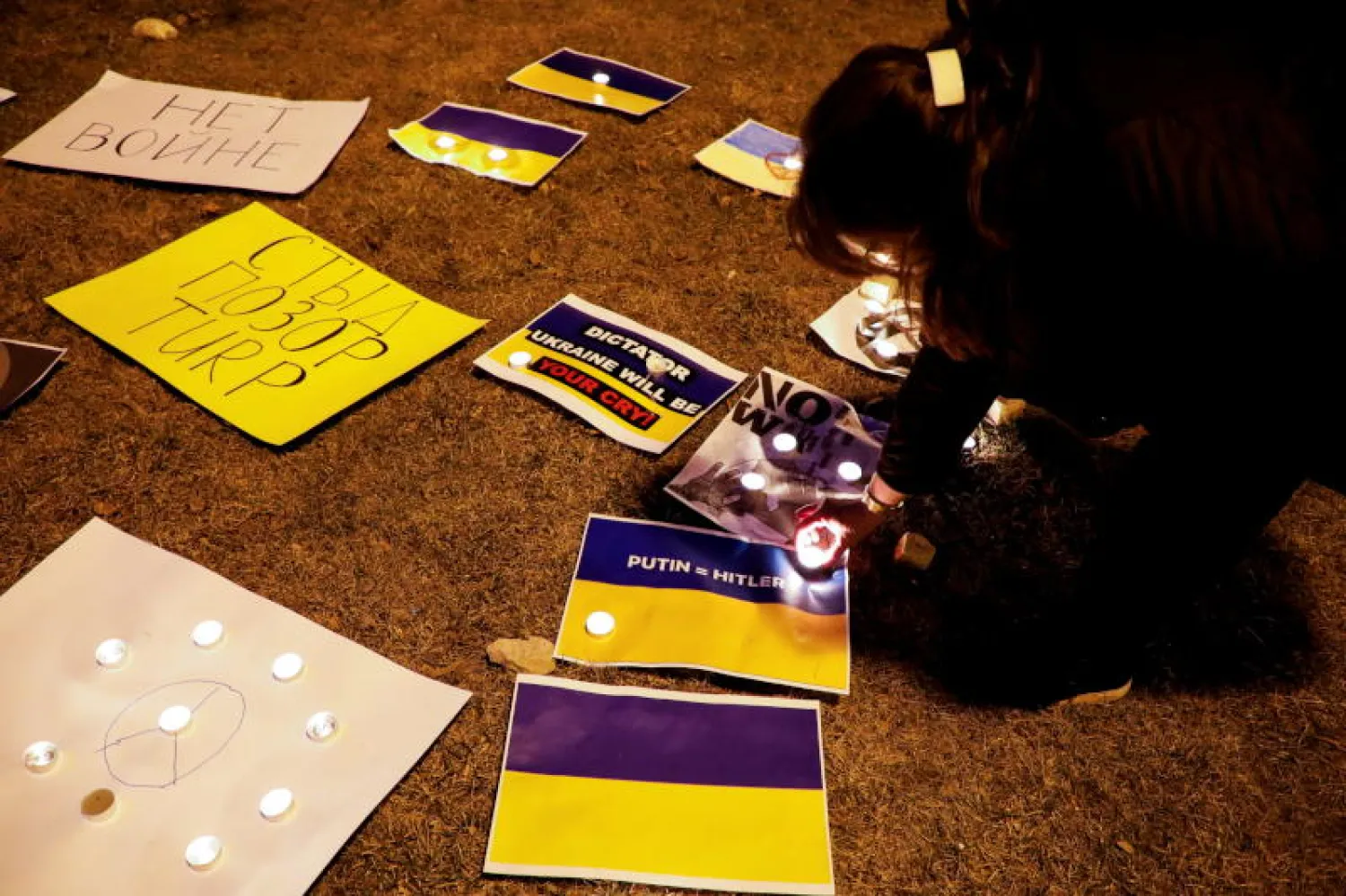 فرد يضيء شمعة خلال احتجاج تضامناً مع الشعب الأوكراني أمام السفارة الروسية في ألبانيا (رويتر)