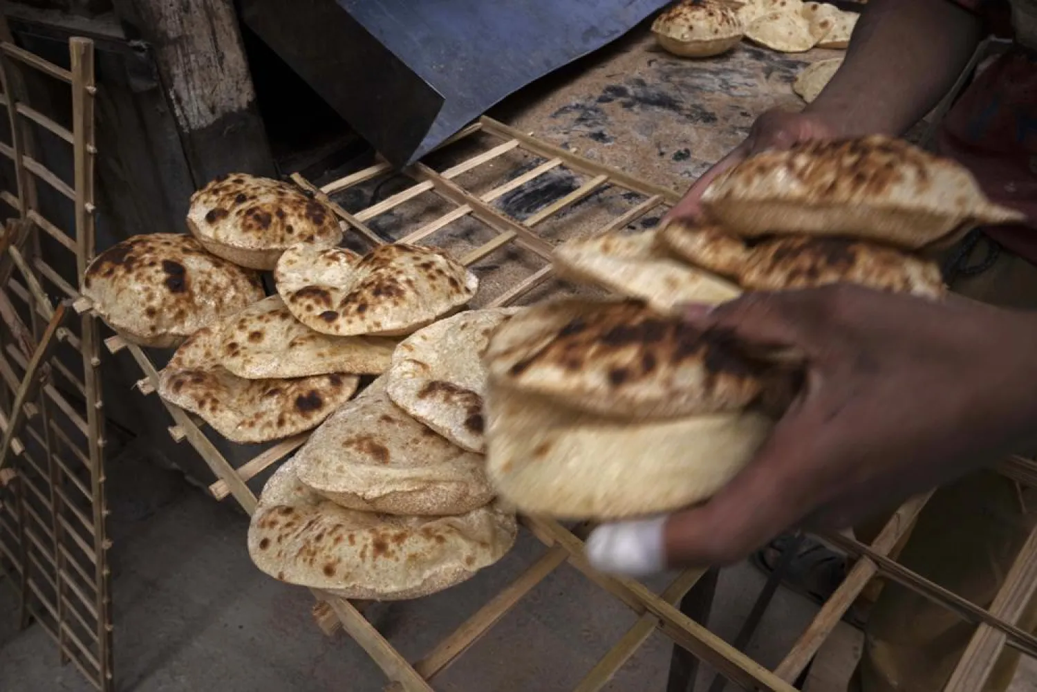 A worker collects Egyptian traditional "baladi" flatbread, at a bakery, in el-Sharabia, Shubra district, Cairo, Egypt, Wednesday, March 2, 2022. (AP)