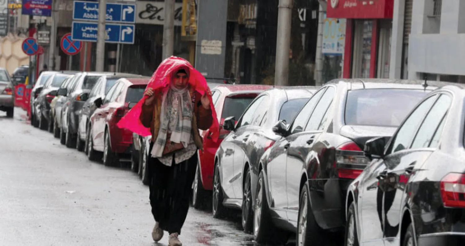 مصرية تحمي نفسها من المطر في القاهرة (إ.ب.أ)