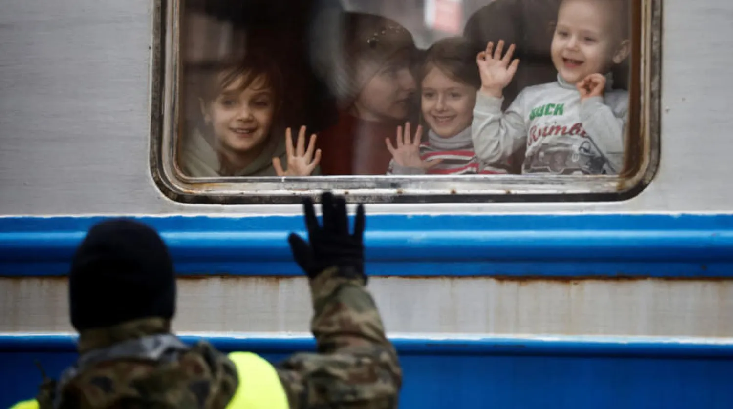 عسكري بولندي يرحب بأطفال لاجئين من أوكرانيا وصلوا أمس بقطار أقلهم من لفيف إلى مدينة برزيميسل (رويترز)