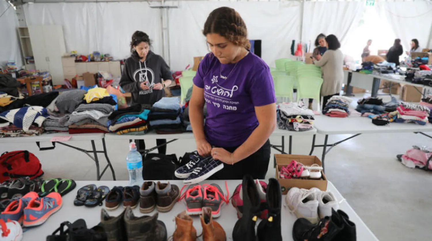 متطوعون إسرائيليون ينظمون ملابس لاجئين من الأيتام اليهود الأوكرانيين قرب القدس (إ.ب.أ)