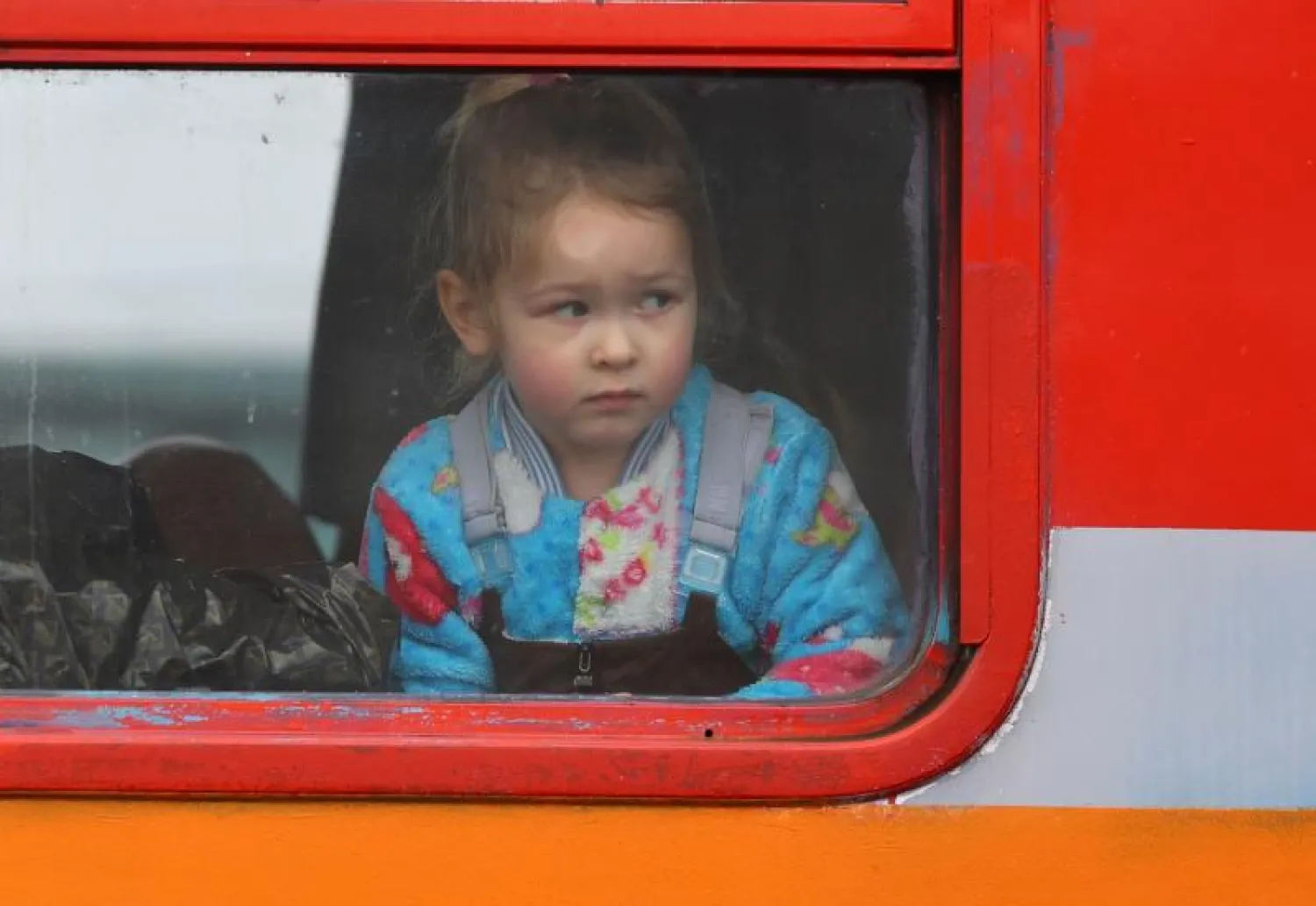 طفلة تنظر من نافذة قطار متجه من أوكرانيا إلى بولندا (رويترز)