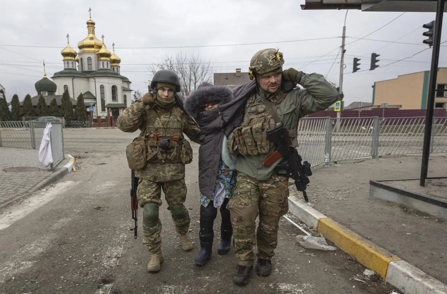 Ukrainian servicemen help an elderly woman, in the town of Irpin, Ukraine, March 6, 2022. (AP)