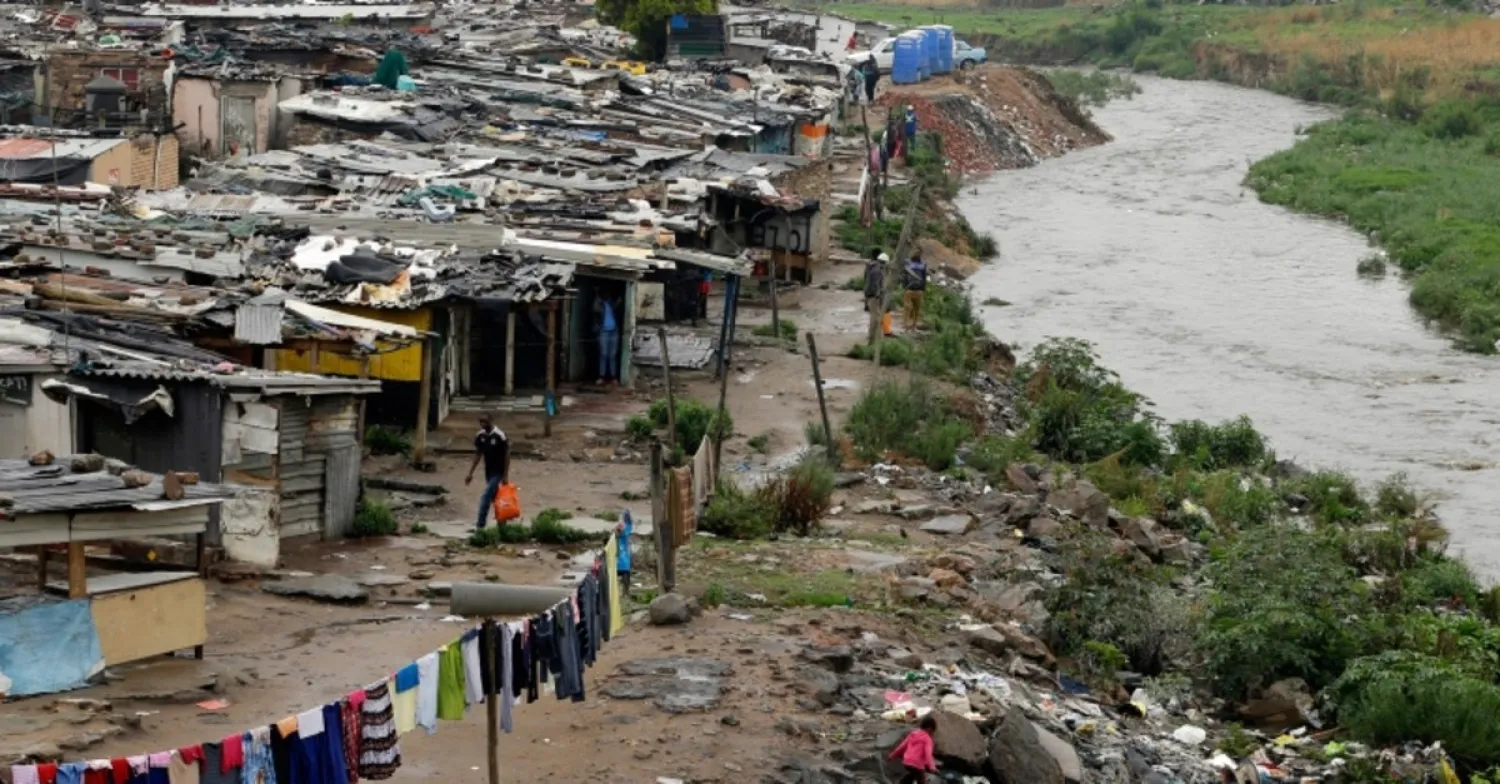 In this Nov. 11, 2014, file photo, a man walks along an informal settlement as a young girl plays next to the polluted Jukskei River in Alexandra, northern Johannesburg, South Africa (AP Photo)