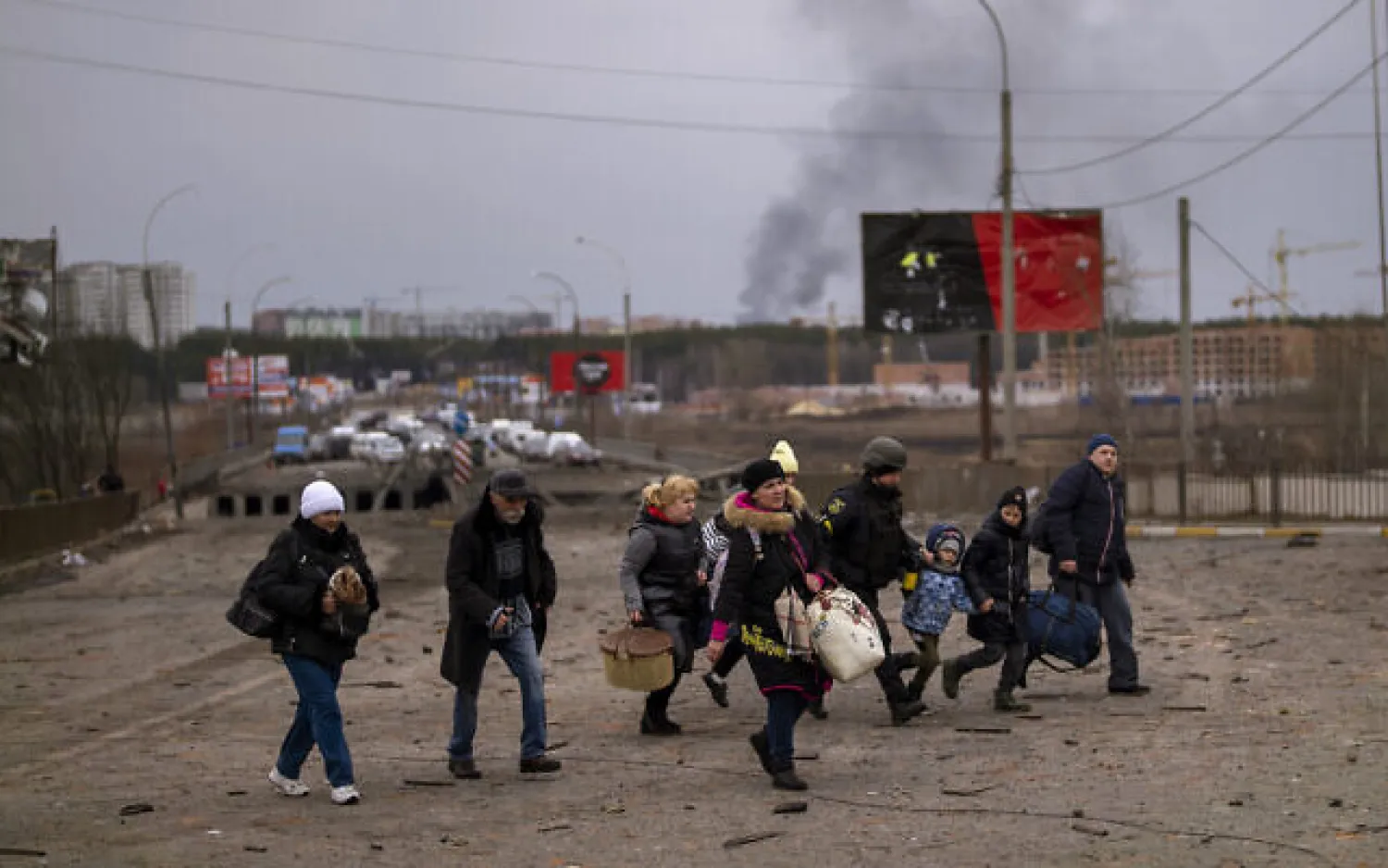 A Ukrainian police officer helps people as artillery echoes nearby while fleeing Irpin in the outskirts of Kyiv, Ukraine, March 7, 2022. (AP Photo/Emilio Morenatti)
