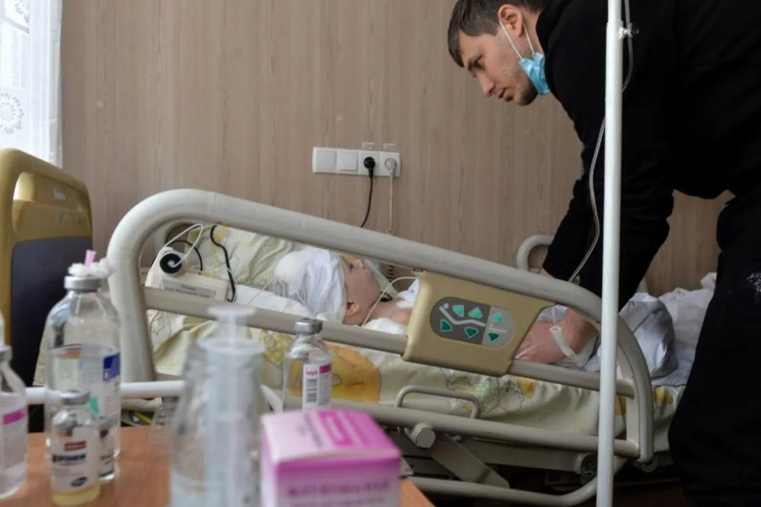 أب يعتني بابنه الذي أصيب في قصف مستشفى بخاركيف (أ.ف.ب)