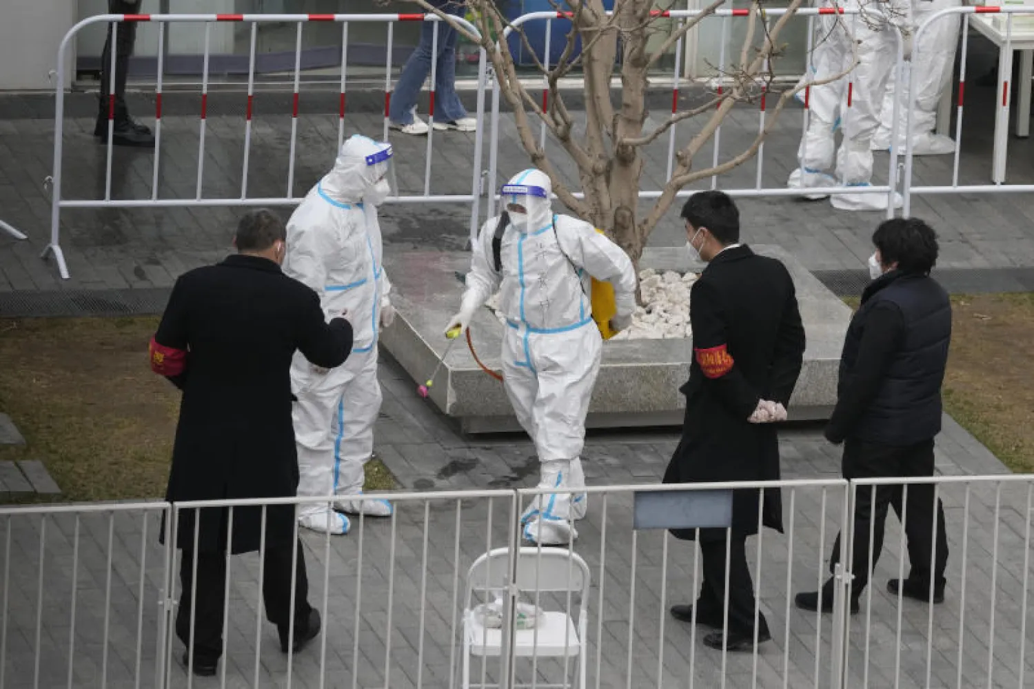 عمال يستعدون لتطهير الزائرين في مبنى مغلق بعد اكتشاف حالة إصابة بفيروس كورونا في بكين (أ.ب)