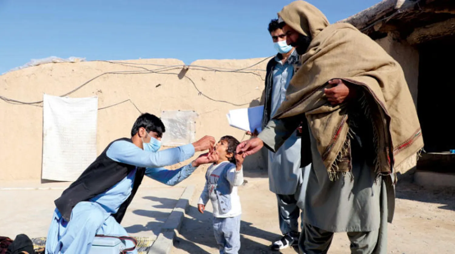 عامل صحي يعطي لقاح شلل الأطفال لطفل بمسجد أثناء حملة التطعيم في قندهار خلال يناير الماضي (إ.ب.أ)
