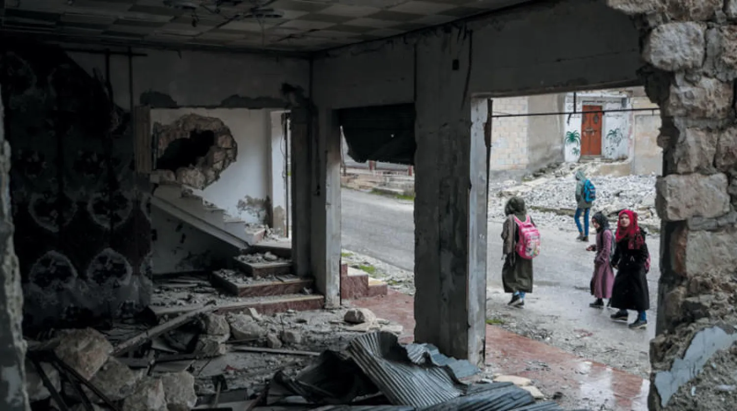 أطفال من قرية بليون بإدلب يعبرون مباني دمرها الطيران الروسي (د.ب.أ)