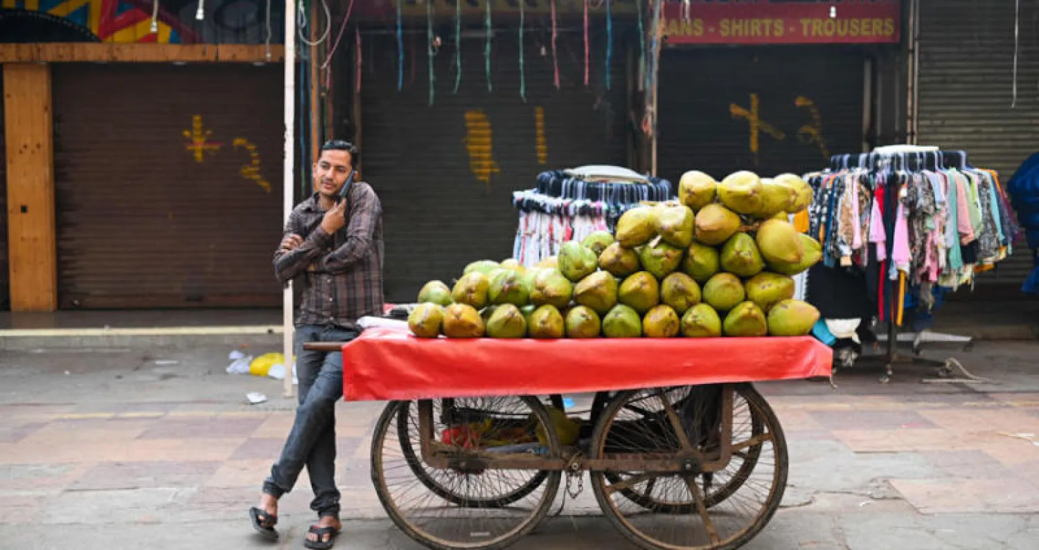 بائع لجوز الهند ينتظر زبائن بأحد الأسواق الهندية في نيودلهي 14 مارس 2022 (أ.ف.ب)