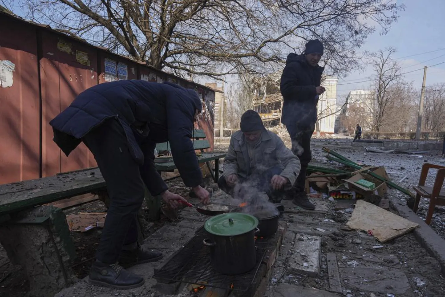 Men cook a meal in a street in Mariupol, Ukraine, Sunday, March 13, 2022. (AP)