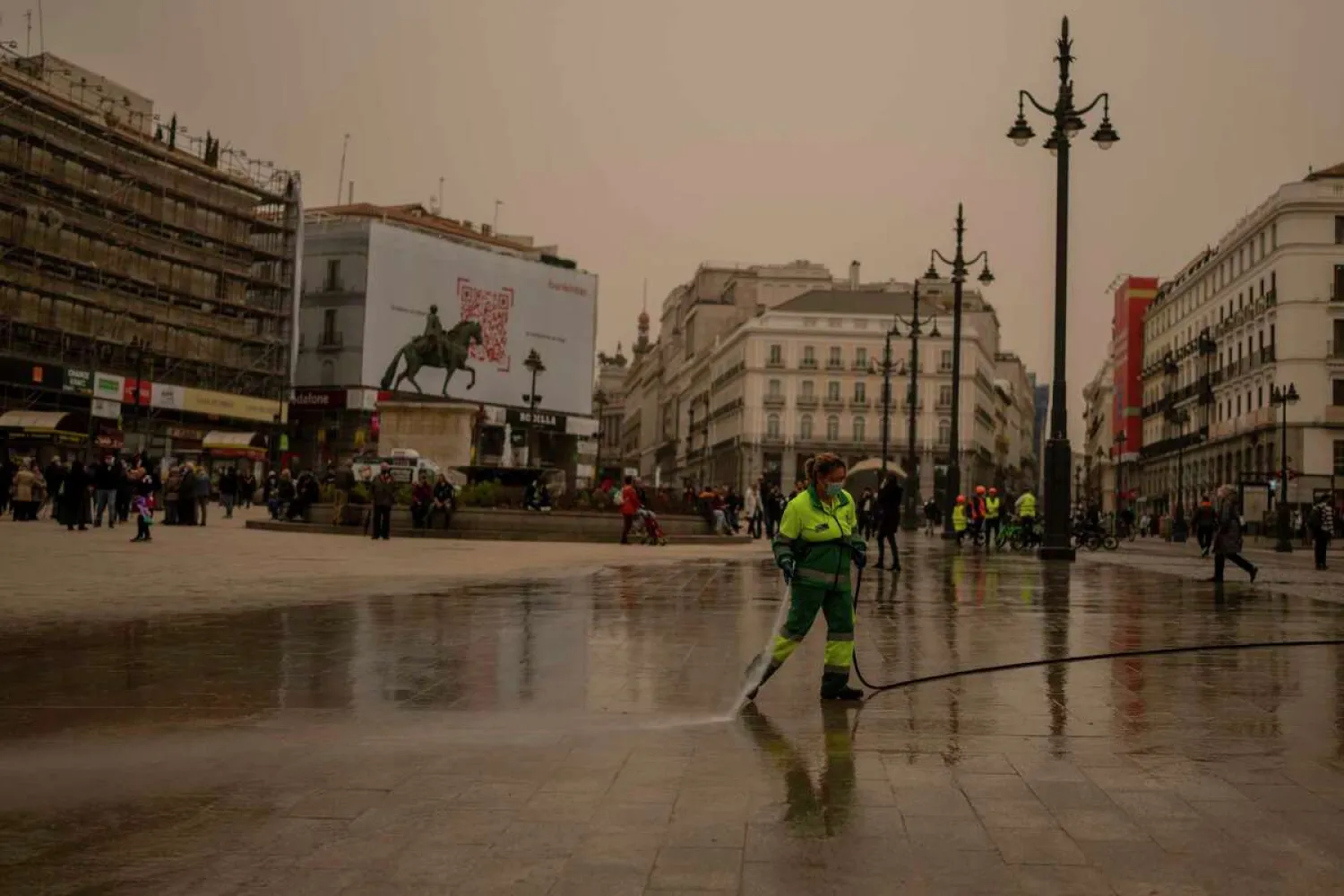 A worker cleans the dust from the Sahara desert at Sol square in Madrid, Spain, Tuesday, March 15, 2022. Manu Fernandez/AP