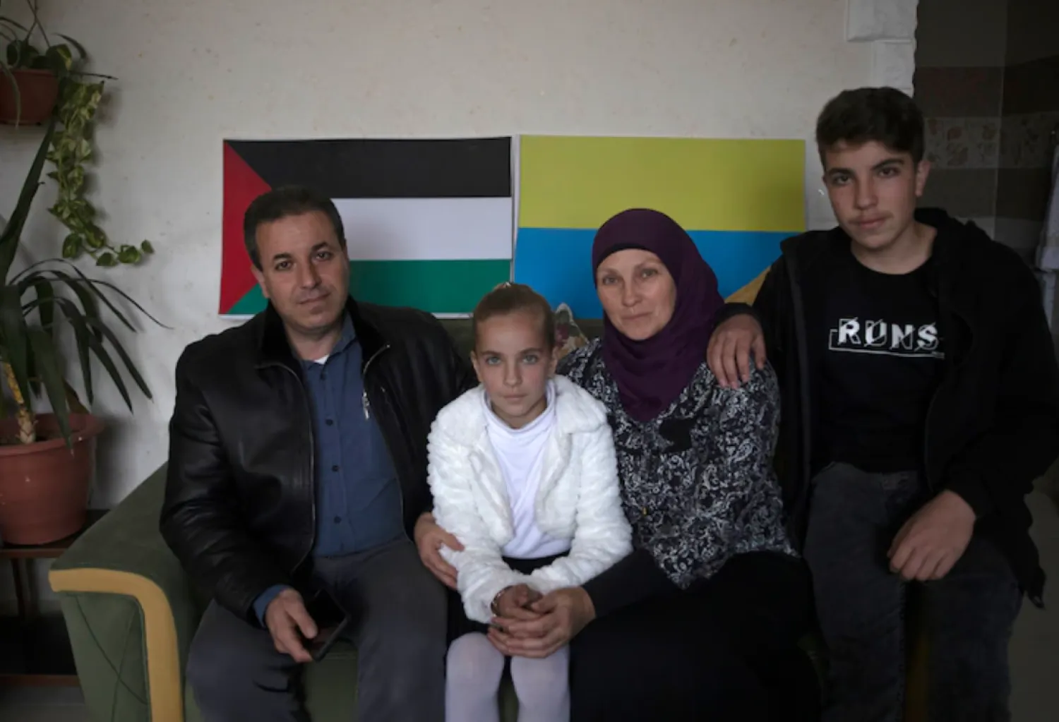 Ukrainian Oksana al-Astal sits with her Palestinian husband and their children as they pose for a photo in front of representations of Palestinian and Ukrainian flags decorating the living room of their home in Khan Younis, southern Gaza Strip, Sunday, March 13, 2022. (AP Photo/ Khalil Hamra)


