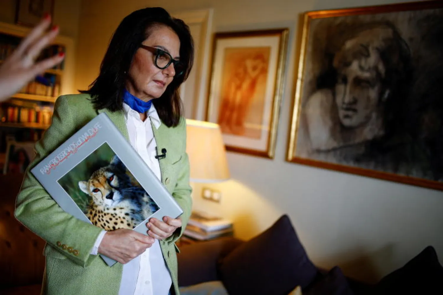 طهران طهباز شقيقة مراد تحمل كتاباً من تأليفه لدى منزلها في مدريد (رويترز)