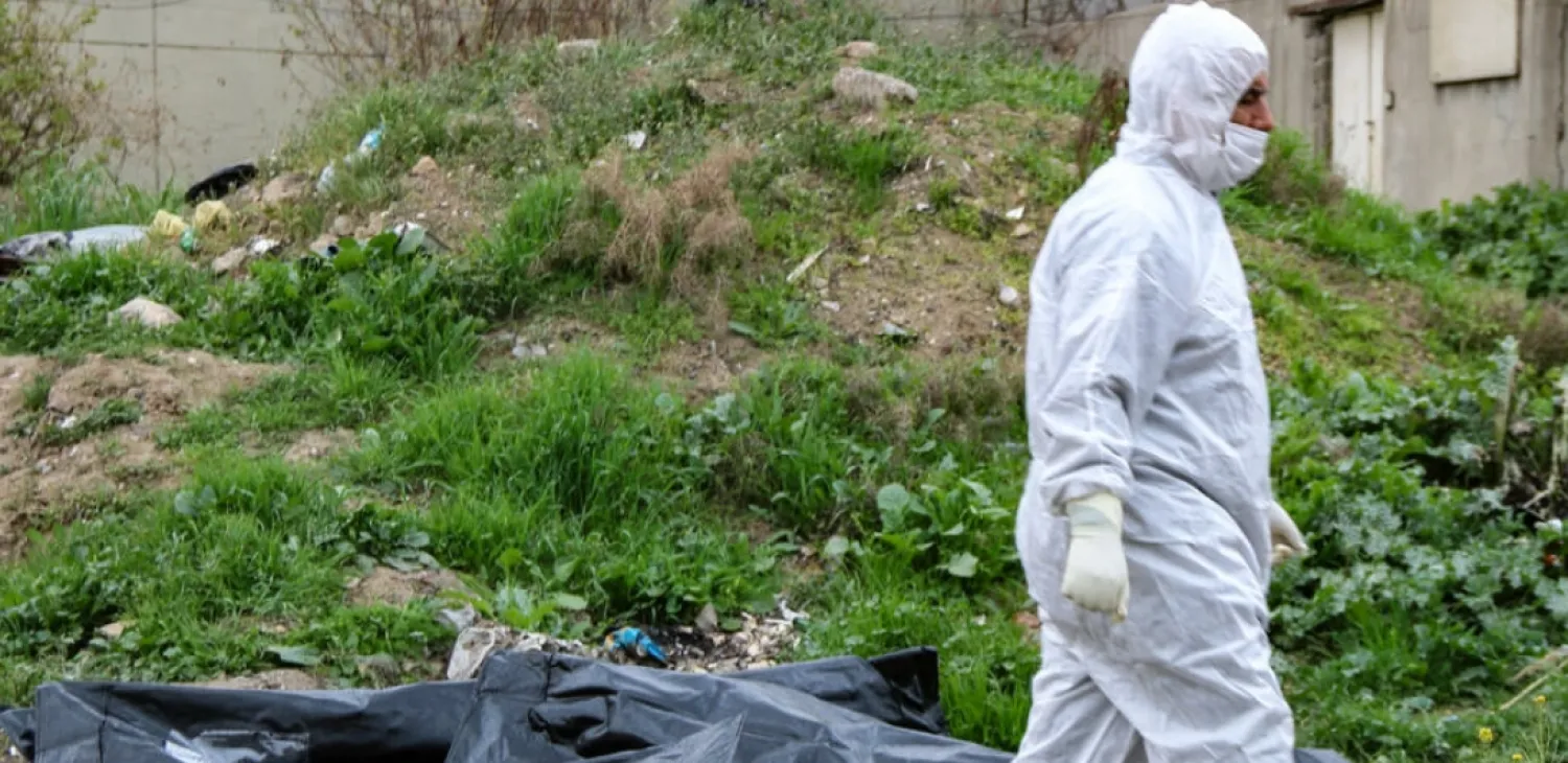 A worker walks past the covered remains of bodies unearthed from a mass grave in the northern Iraqi city of Mosul. AFP