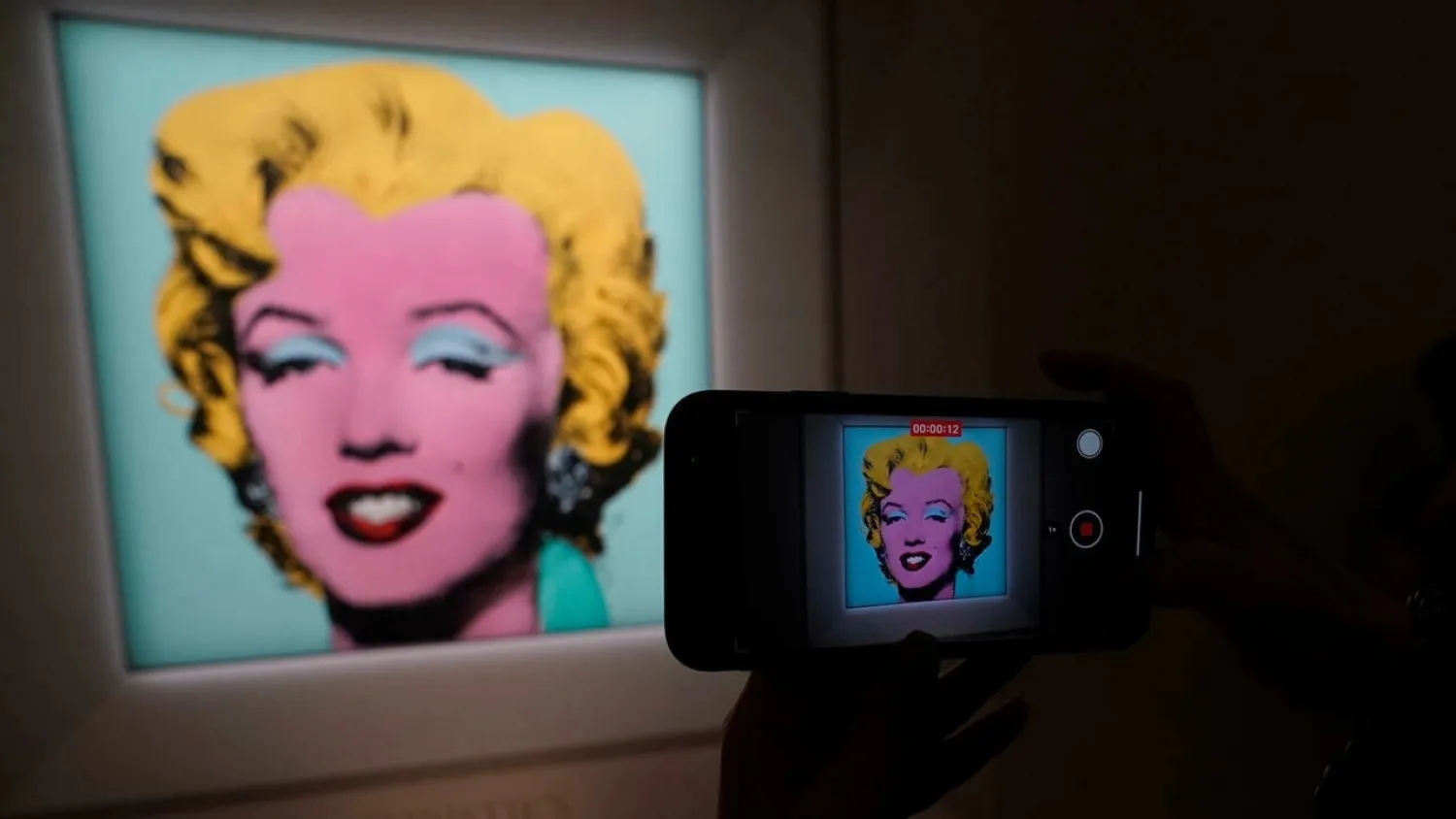 A journalist takes photos during a press preview March 21, 2022 in New York as Christie's announces "Shot Sage Blue Marilyn" by Andy Warhol will lead its Marquee Week of sales in May. (AFP)