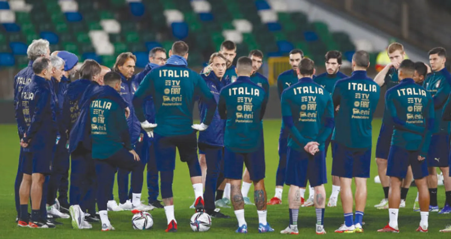 لاعبو إيطاليا يستمعون لتعليمات مدربهم مانشيني قبل خوض الملحق الحاسم (رويترز)
