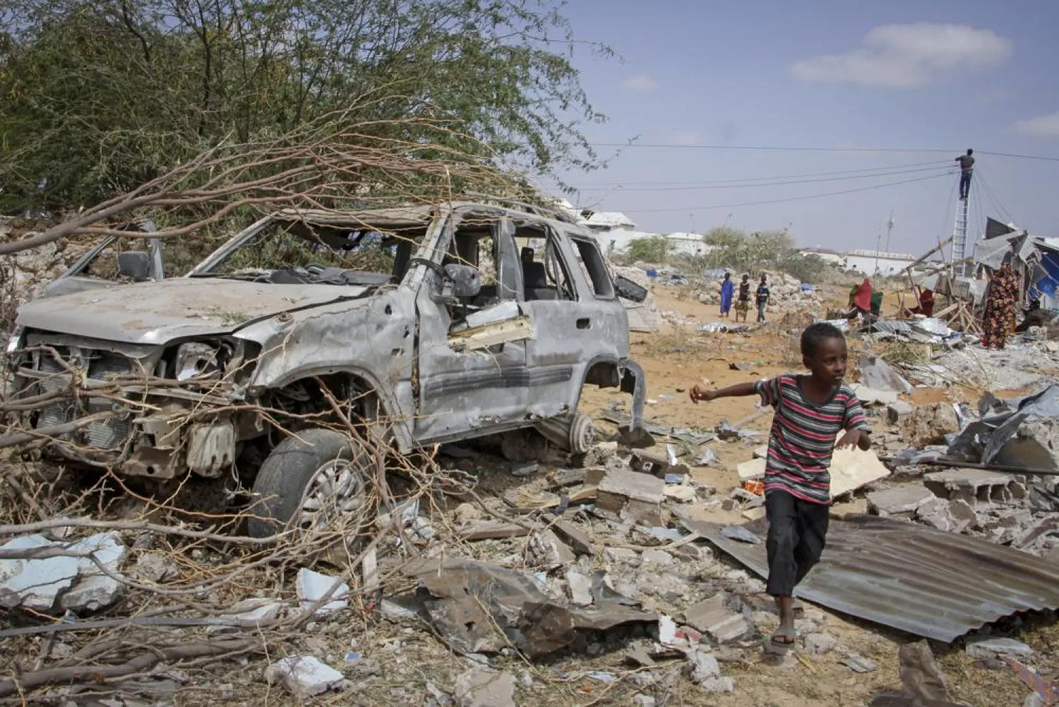 A young boy runs past the wreckage of a vehicle destroyed in an attack on police and checkpoints on the outskirts of the capital Mogadishu, Somalia Wednesday, Feb. 16, 2022. (AP File Photo/Farah Abdi Warsameh)

