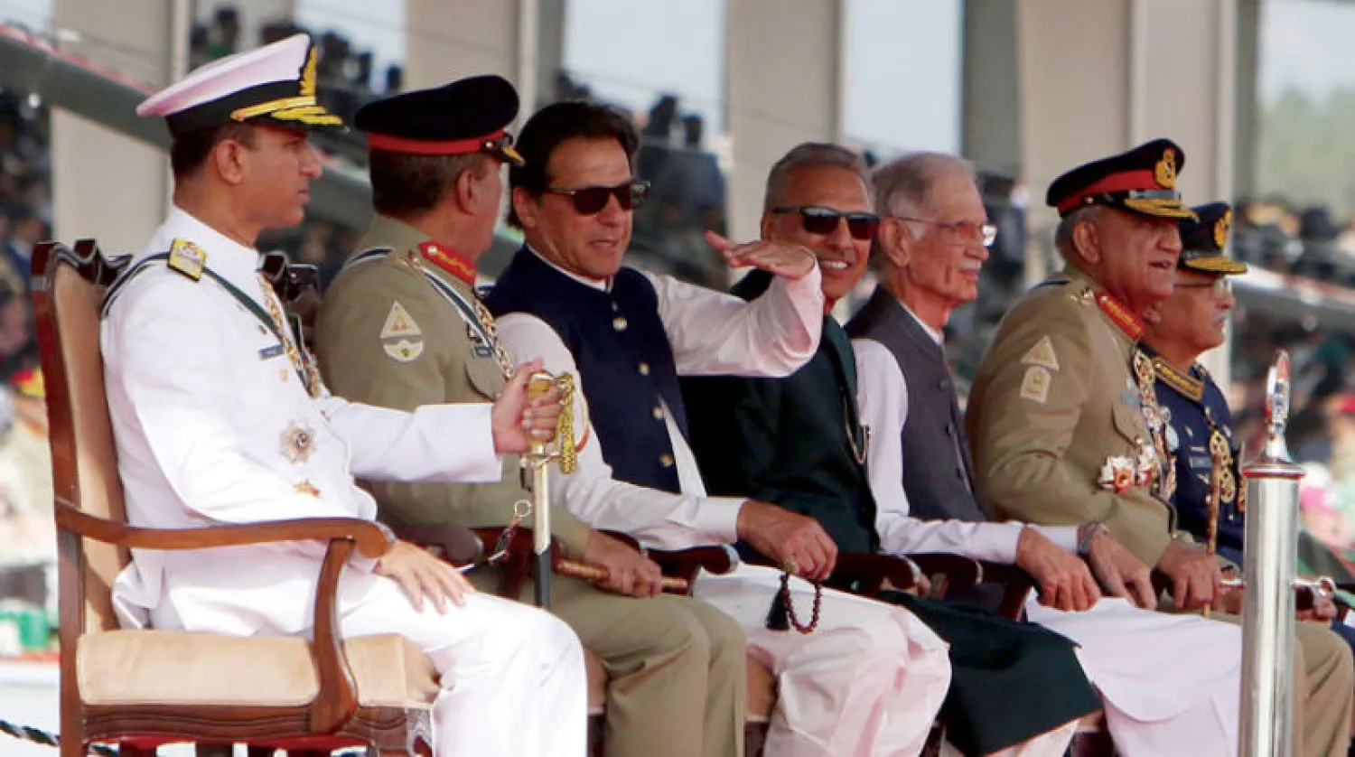 رئيس الوزراء الباكستاني عمران خان (وسط) والرئيس الباكستاني عارف علوي يشاهدان الطائرات المقاتلة التابعة للقوات الجوية الباكستانية خلال حفل بمناسبة اليوم الوطني الباكستاني في إسلام آباد أول من أمس (إ.ب.أ)