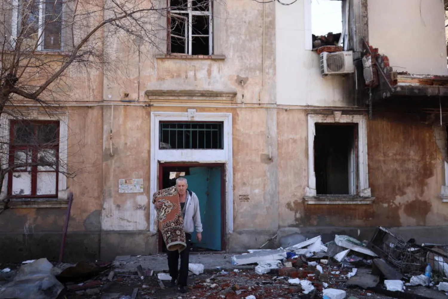 أوكراني يخرج من مبنى مدمّر بقصف روسي على مدينة ميكولايف (رويترز)