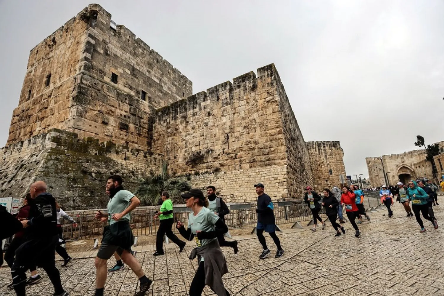 Runners pass Jaffa Gate as they take part in the Jerusalem Marathon, which includes international competitors, after Israel eased coronavirus disease (COVID-19) restrictions on tourists entering the country, in Jerusalem March 25, 2022. (Reuters)