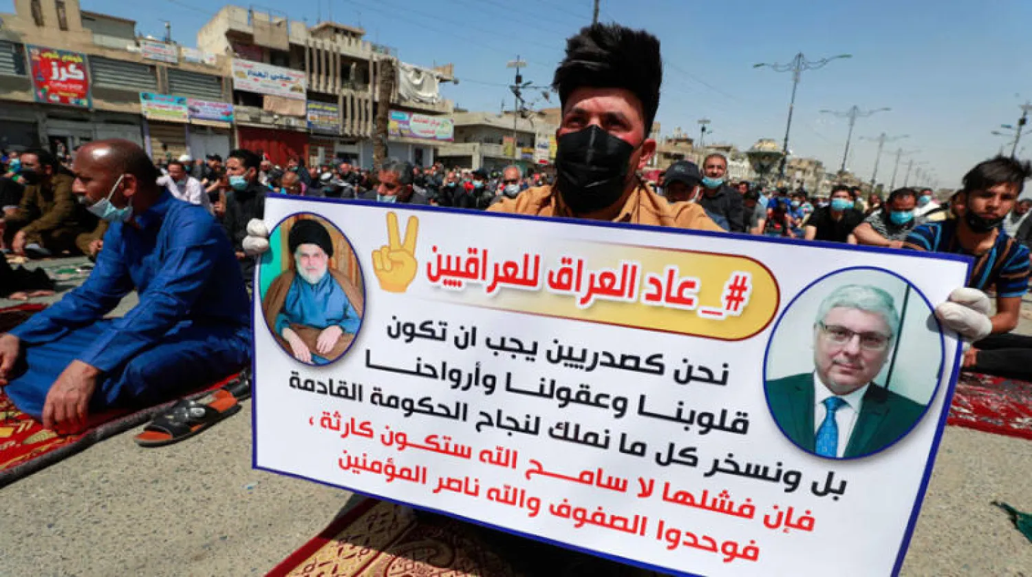 أحد مؤيدي مقتدى الصدر يرفع صورته وصورة سفير العراق في لندن جعفر الصدر الذي يُطرح اسمه مرشحاً لتشكيل الحكومة العراقية الجديدة، وذلك خلال صلاة الجمعة في مدينة الصدر شرق بغداد أمس (أ.ف.ب)