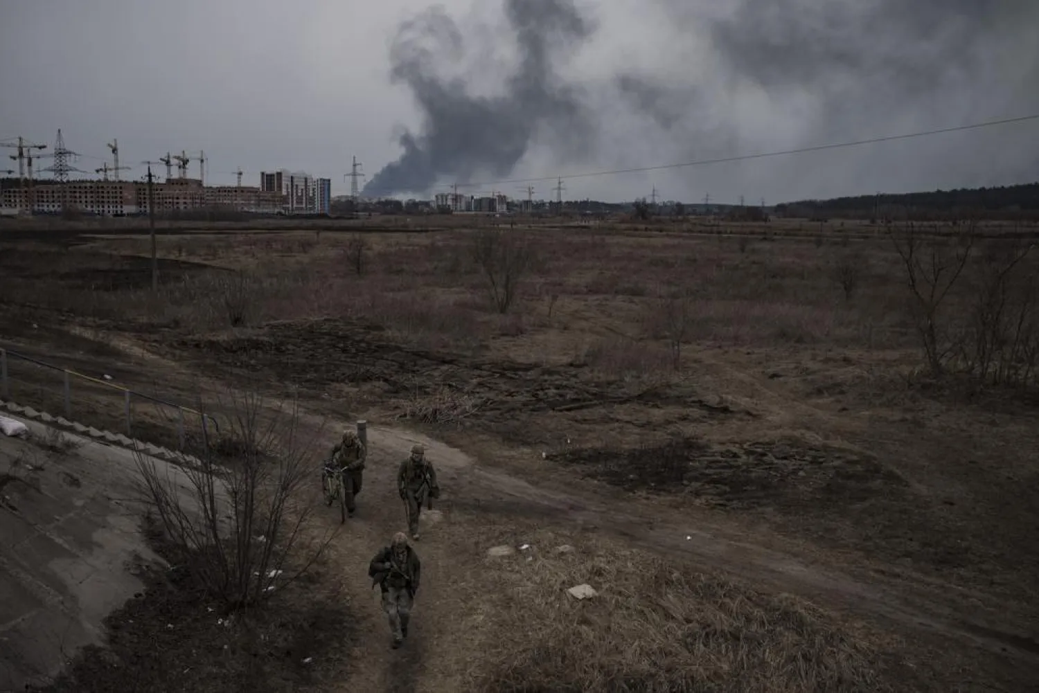 Soldiers walk on a path as smoke billows from the town of Irpin, on the outskirts of Kyiv, Ukraine, Saturday, March 12, 2022. (AP)