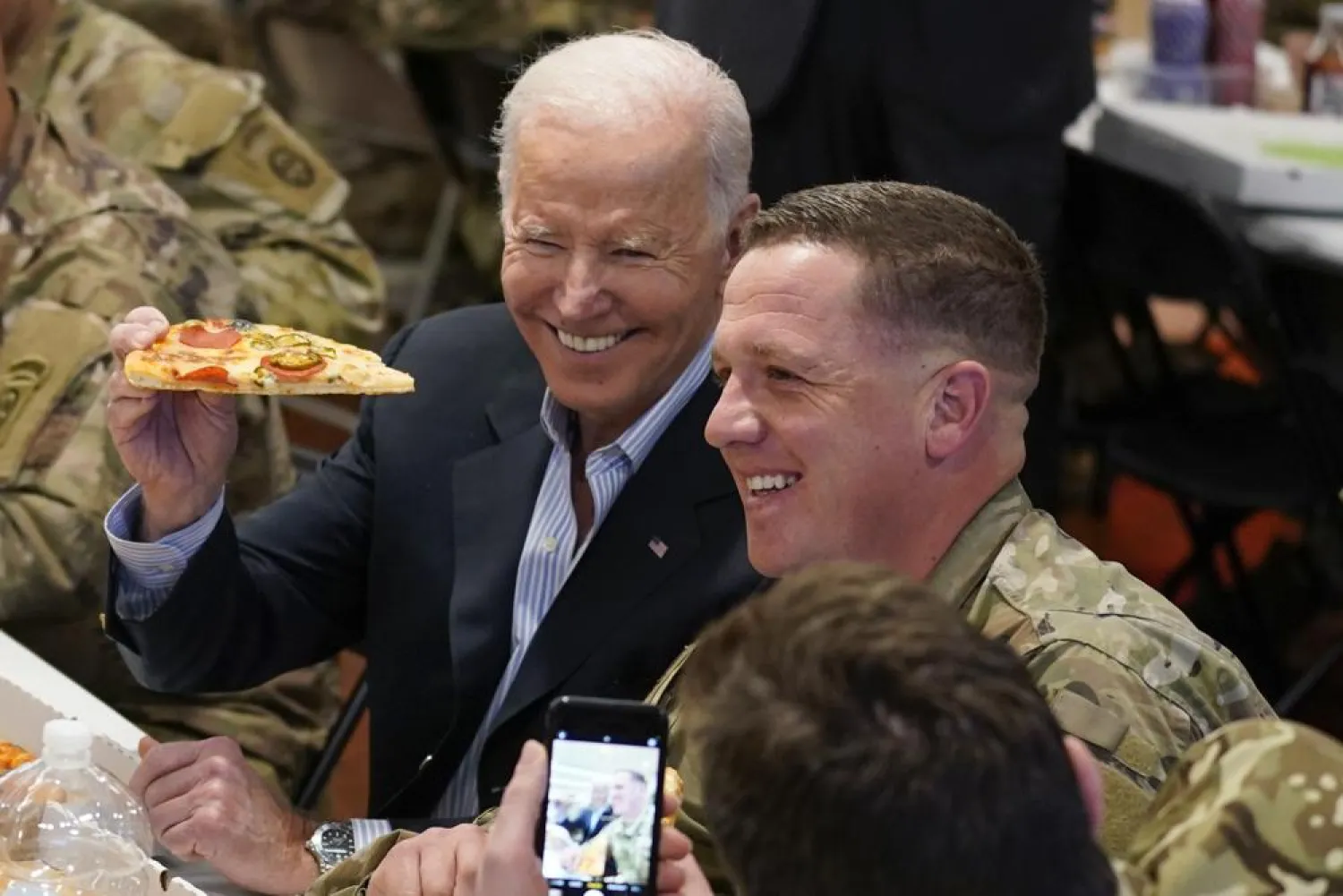 President Joe Biden holds a piece of pizza as he posed for a photo during a visit with members of the 82nd Airborne Division at the G2A Arena, Friday, March 25, 2022, in Jasionka, Poland. (AP)