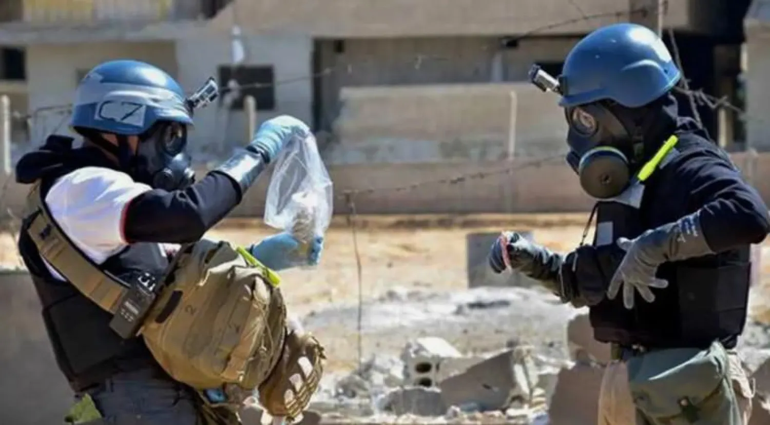 خبراء من الأمم المتحدة يحملون عينة من منطقة تعرضت لهجوم بالأسلحة الكيماوية في سوريا (أ.ب)