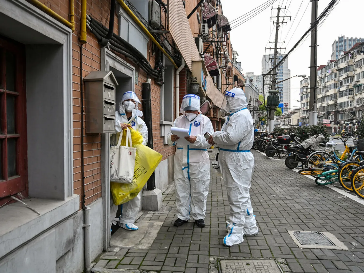 Health workers wearing protective gear work on a street in Jing'an district in Shanghai. Hector RETAMAL AFP
