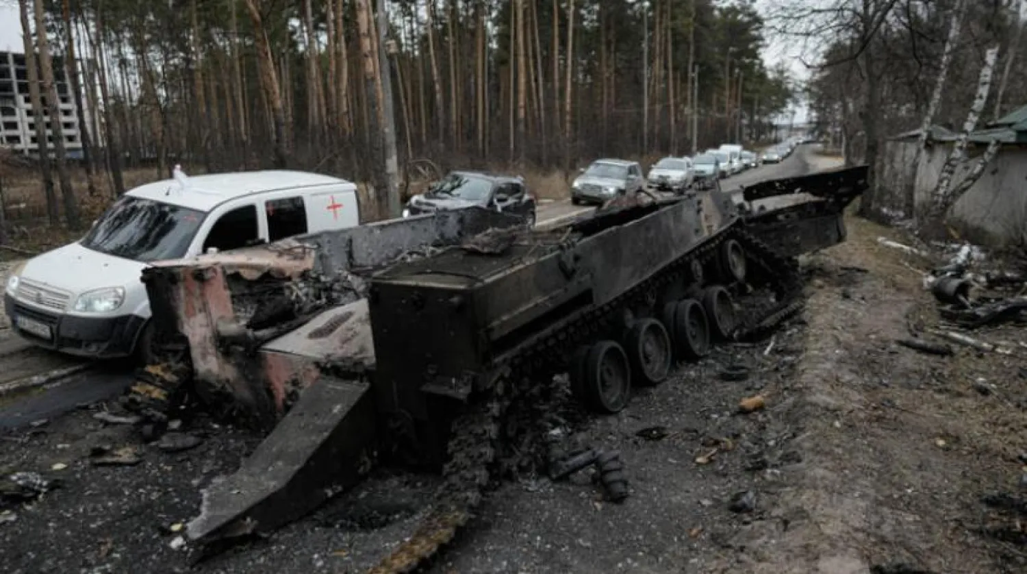 9 Mart’ta İrpin’de yanmış bir Rus tankının yanından geçen arabalar (AP)