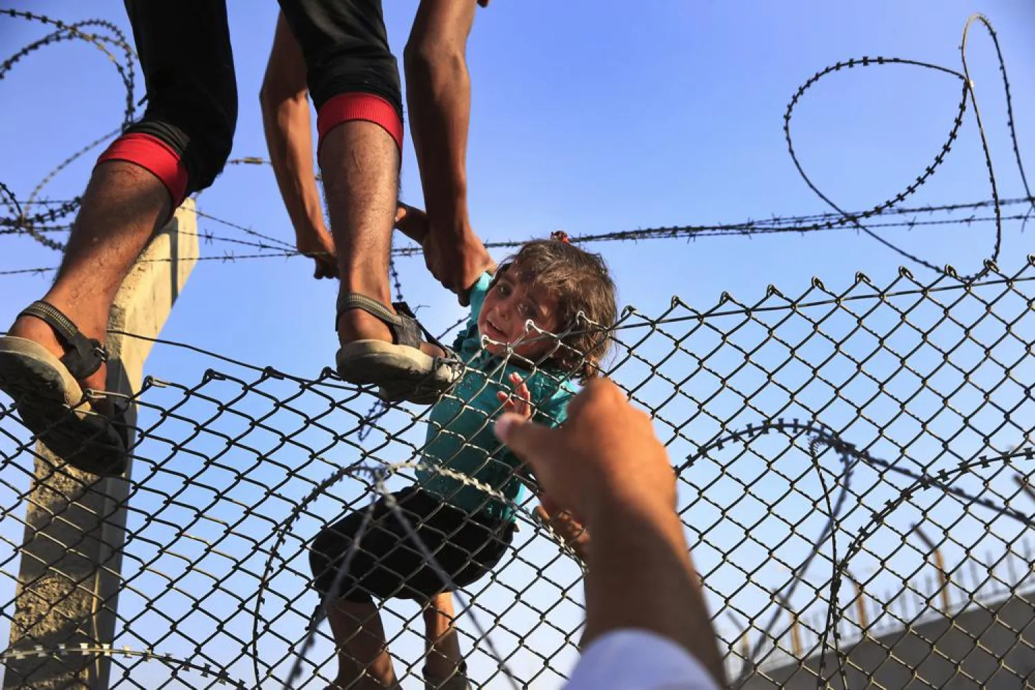 A Syrian refugee lifts a baby over the border fence into Turkey from Syria in Akcakale, Sanliurfa province, southeastern Turkey on June 14, 2015. (AP)
