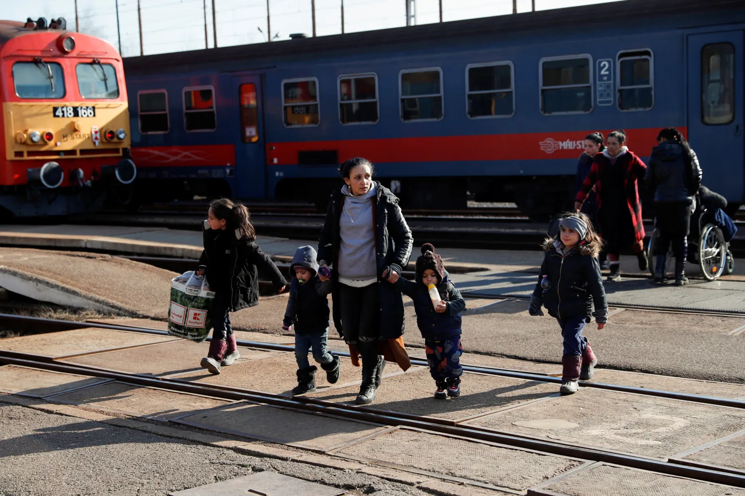 A woman who arrived from Ukraine to Hungary walks with children as they wait to be transferred to a shelter, after Russia launched a massive military operation against Ukraine, in Zahony, Hungary, February 27, 2022. REUTERS/Bernadett Szabo