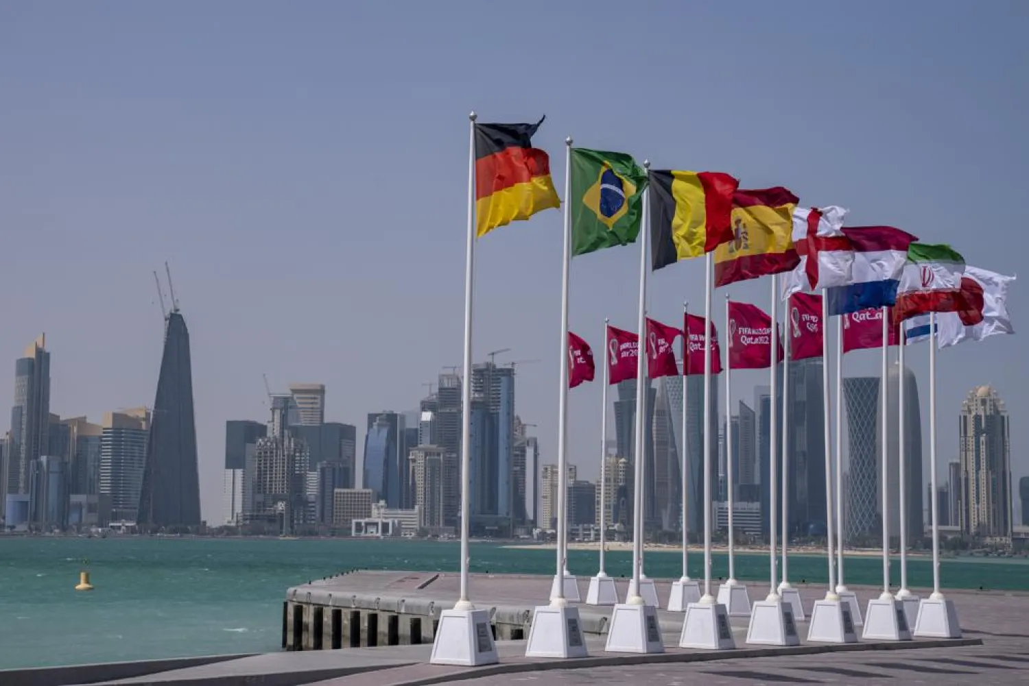 Flags of some of the qualified countries of the World Cup wave at the seafront in Doha, Qatar, Tuesday, March 29, 2022. (AP)