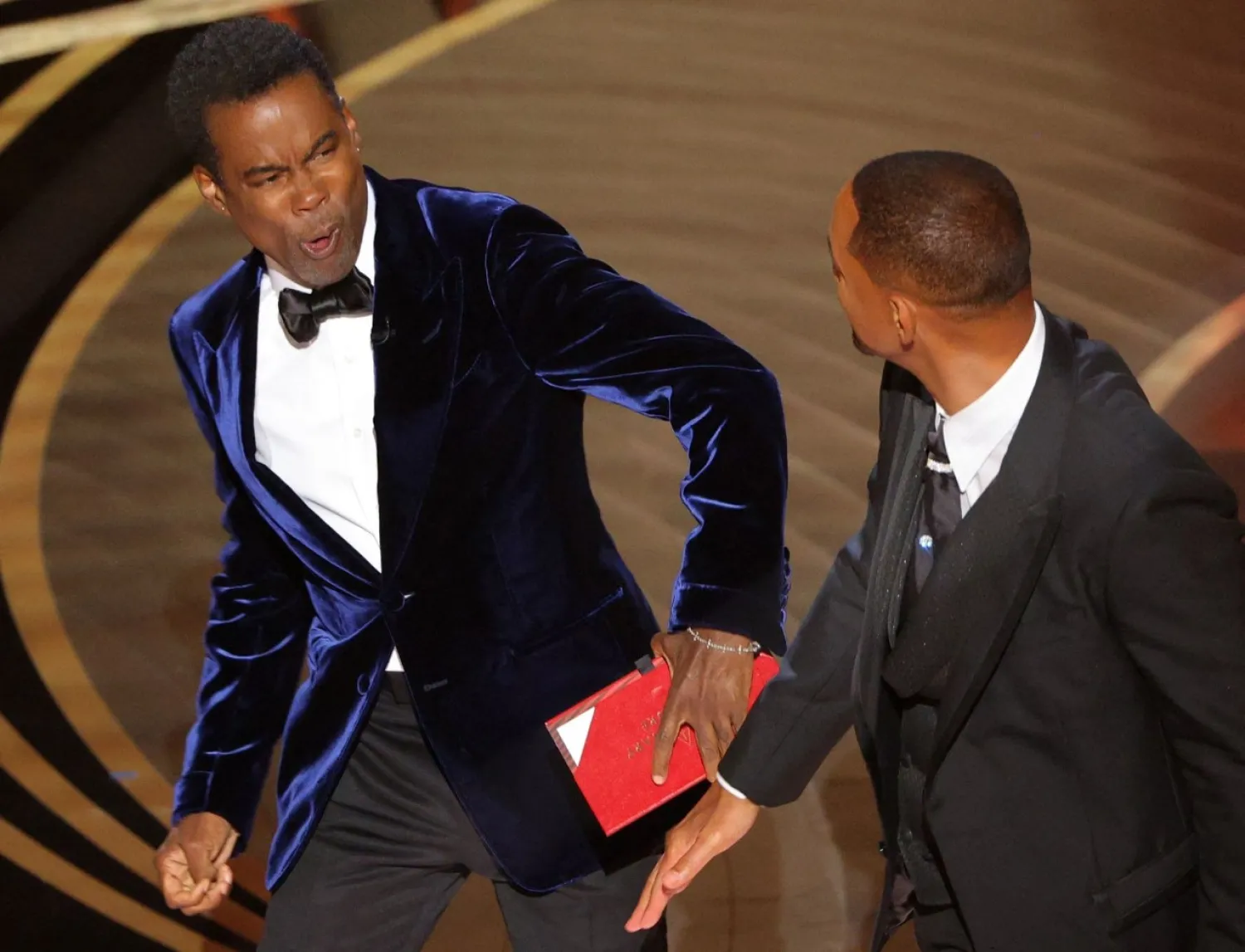 Will Smith (R) hits at Chris Rock as Rock spoke on stage during the 94th Academy Awards in Hollywood, Los Angeles, California, US, March 27, 2022. REUTERS/Brian Snyder