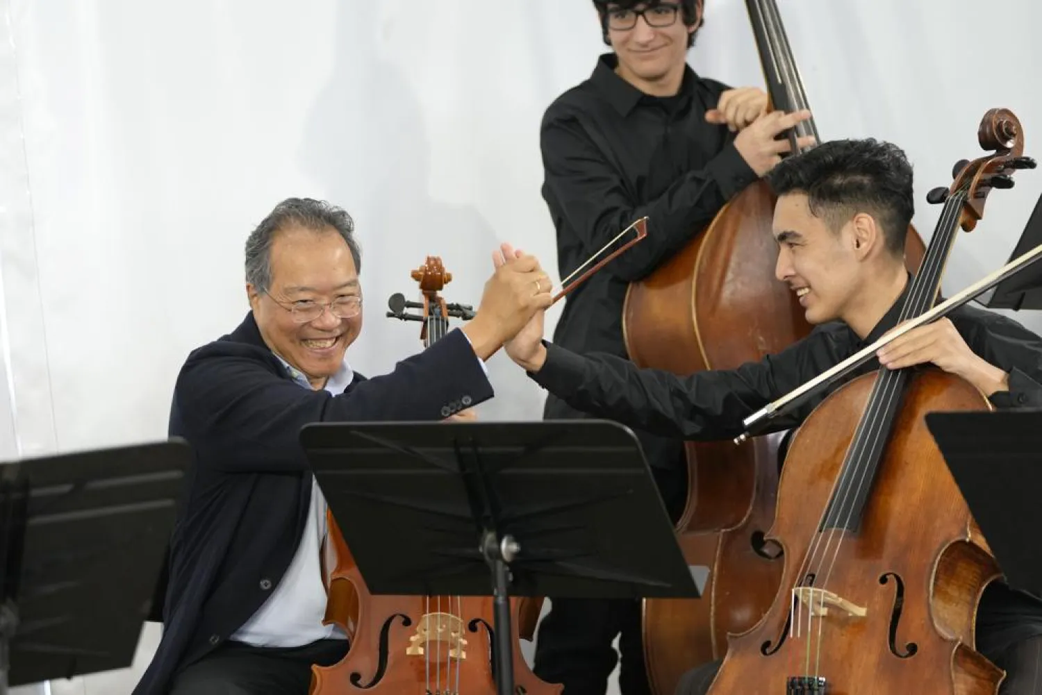 World renowned US cellist Yo-Yo Ma clasps hands with Afghan cellist Mohammad Sami, right, after their performance at the Music School of the National Conservatory in Lisbon, Tuesday, March 29, 2022. (AP)