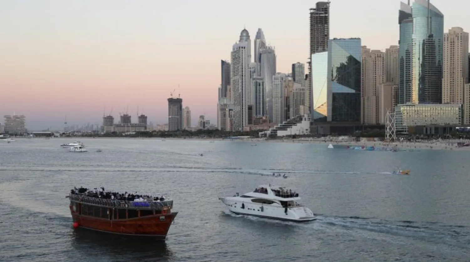 Tourists on a yacht as they pass a traditional dhow serving a dinner cruise, in Dubai, United Arab Emirates, Tuesday, Jan. 12, 2021. (AP Photo/Kamran Jebreili)
