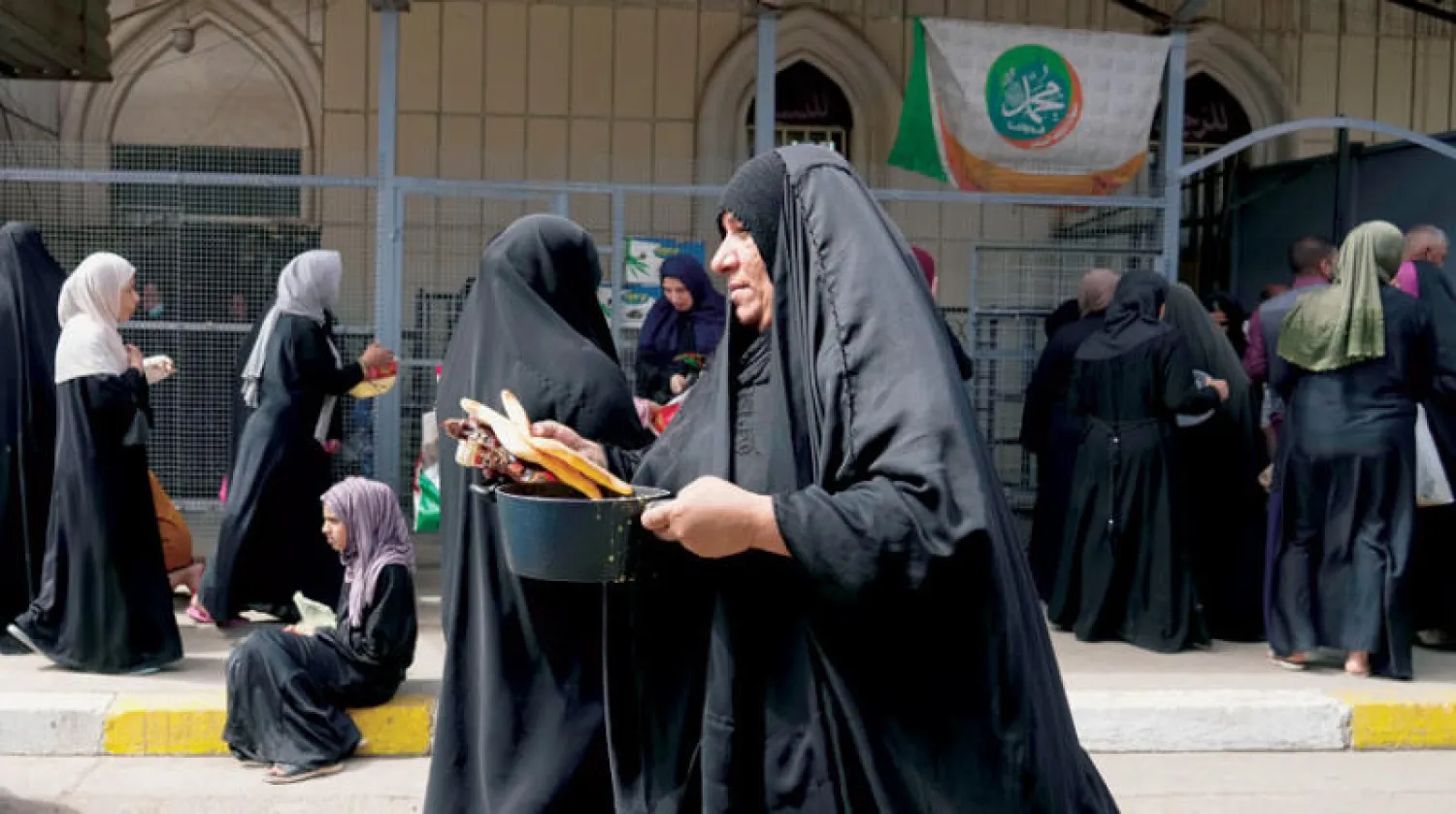 عراقيات أمام مركز يوزع مساعدات غذائية استعداداً للإفطار بمسجد في بغداد أمس (أ.ب)