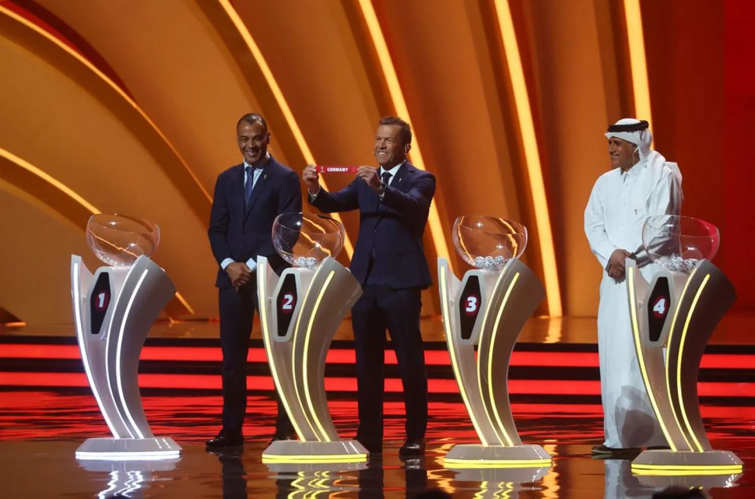 Soccer Football - World Cup - Final Draw - Doha Exhibition & Convention Center, Doha, Qatar - April 1, 2022 Draw assistant Lothar Matthaus draws Germany as Cafu and Adel Ahmed MalAllah look on REUTERS/Ahmed Jadallah