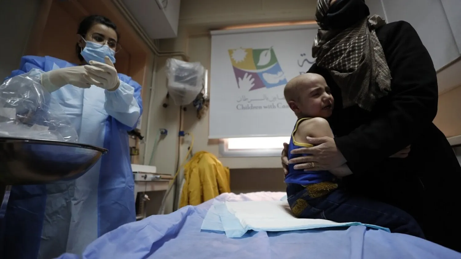A woman holds her crying child at the cancer ward of the Children's Hospital in Damascus, Syria, Monday, March. 7, 2022. (AP)