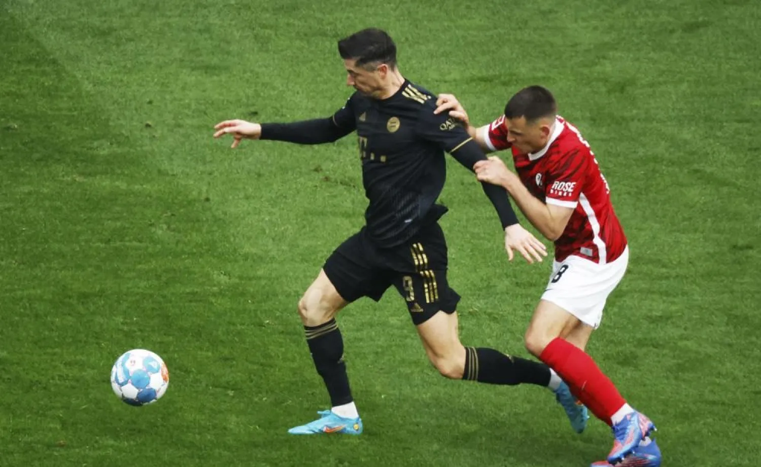 Munich's Robert Lewandowski, left, and Freiburg's Maximilian Eggestein challenge for the ball during the German Bundesliga match between SC Freiburg and Bayern Munich in Freiburg, Germany, Saturday, April 2, 2022. (AP)
