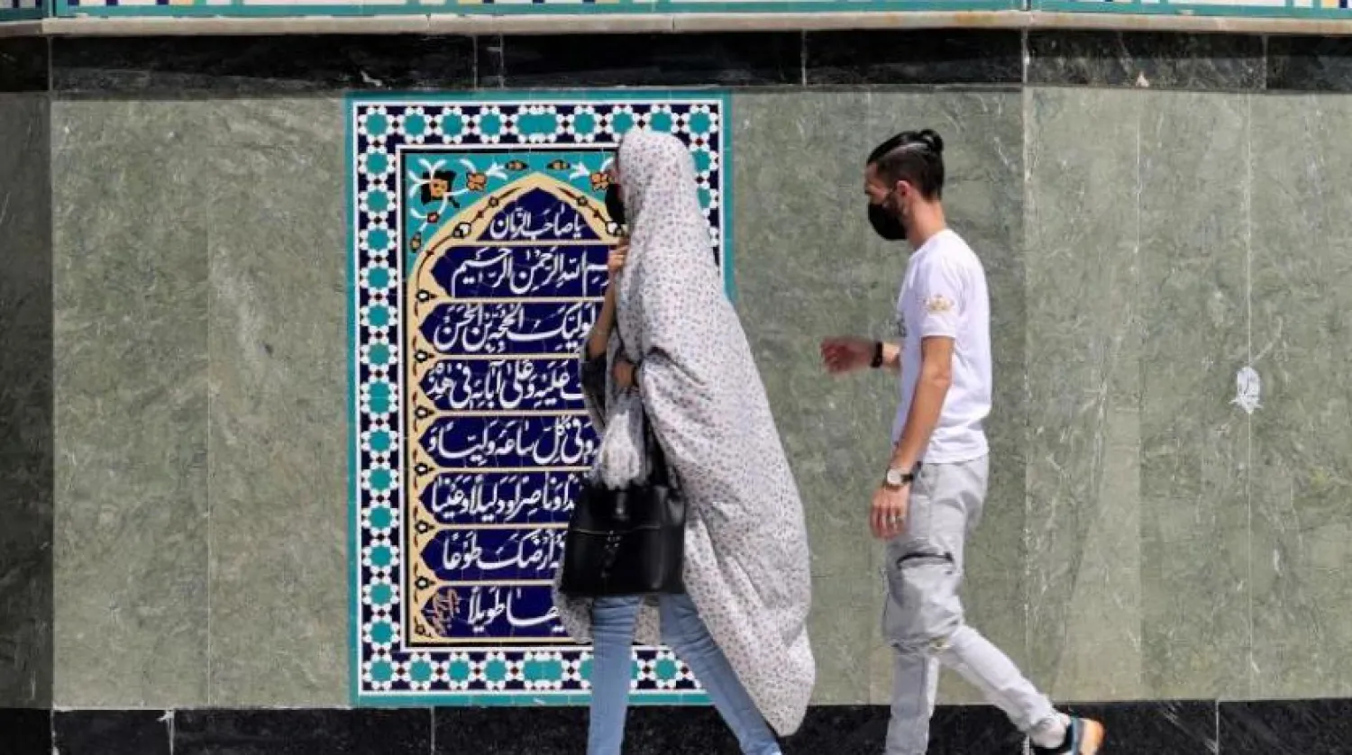İranlı bir kadın, Tahran’ın kuzeyinde bulunan bir duvarın önünden geçiyor (AFP)