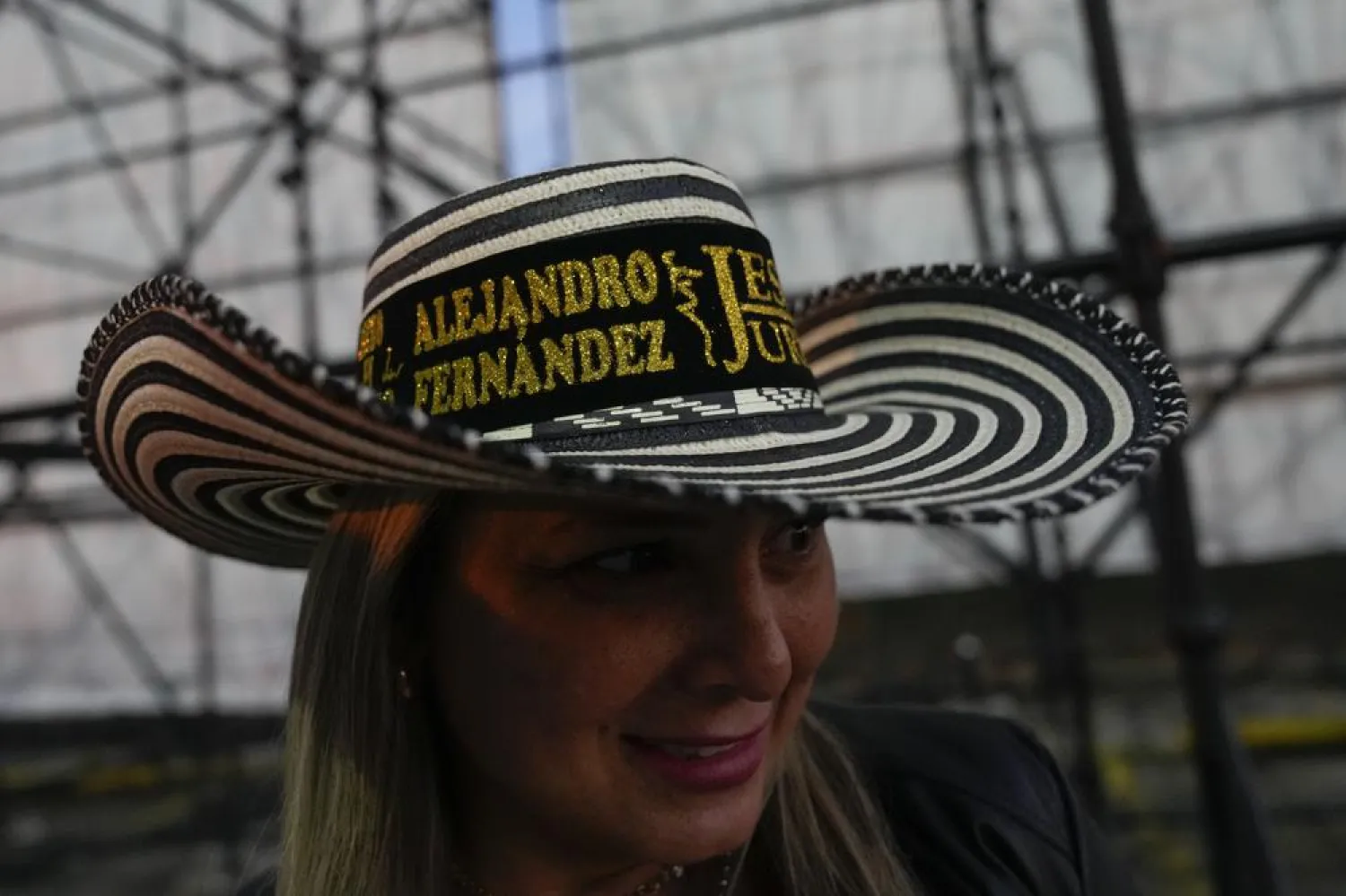 A fan wears a traditional Colombian hat with the name of Mexican singer Alejandro Fernandez and Colombian singer Jessi Uribe as she lines up to attend their concert in Caracas, Venezuela, March 3, 2022. (AP)