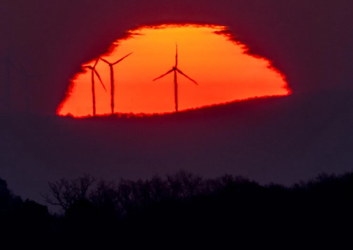 Wind turbines stand in front of the rising sun in Frankfurt, Germany, Friday, March 11, 2022. (AP)