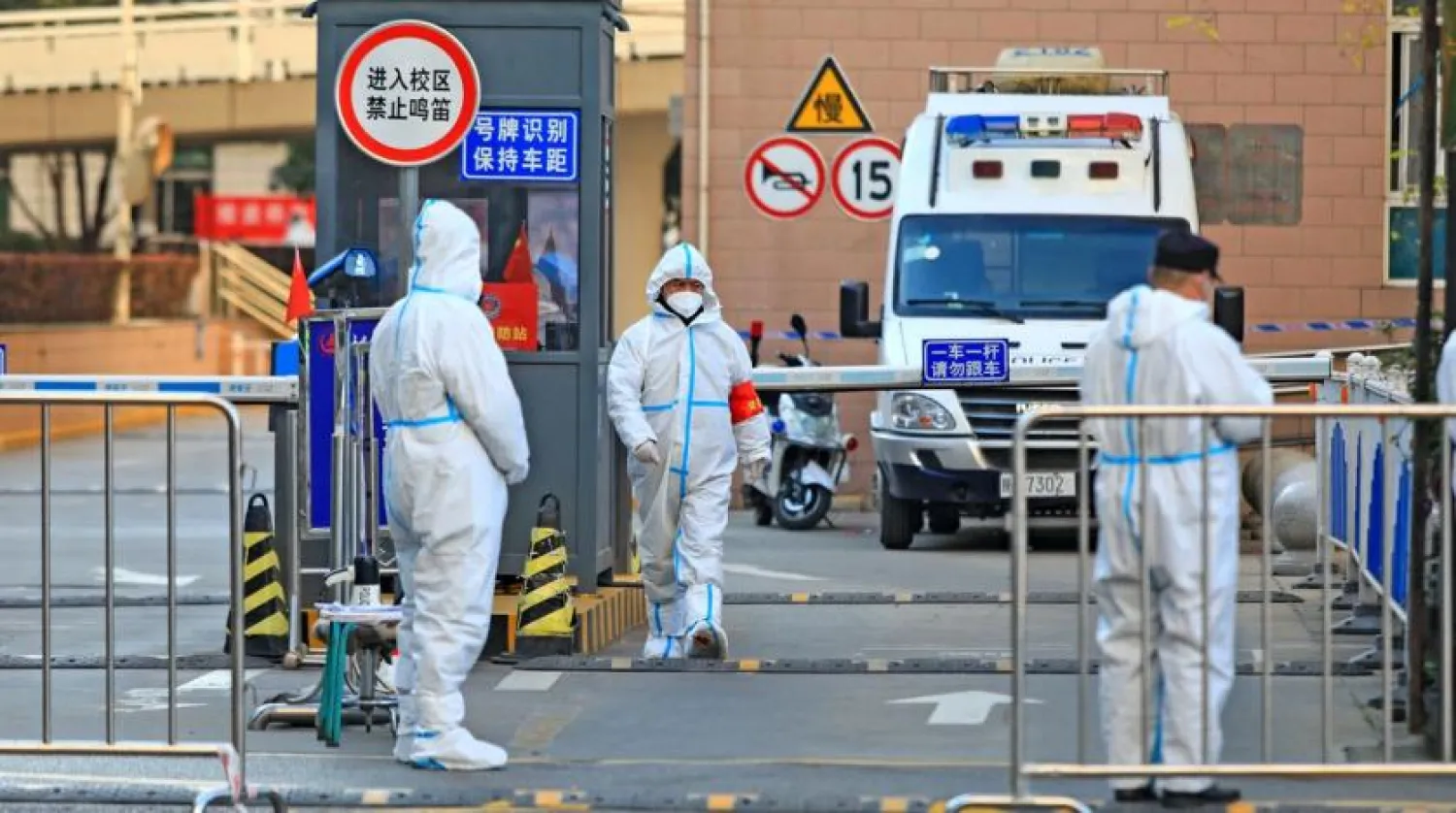 Workers in protective suits stand at an entrance to a university's residential area under lockdown following the coronavirus disease (COVID-19) outbreak in Xian, Shaanxi province, China December 20, 2021. China Daily via REUTERS

