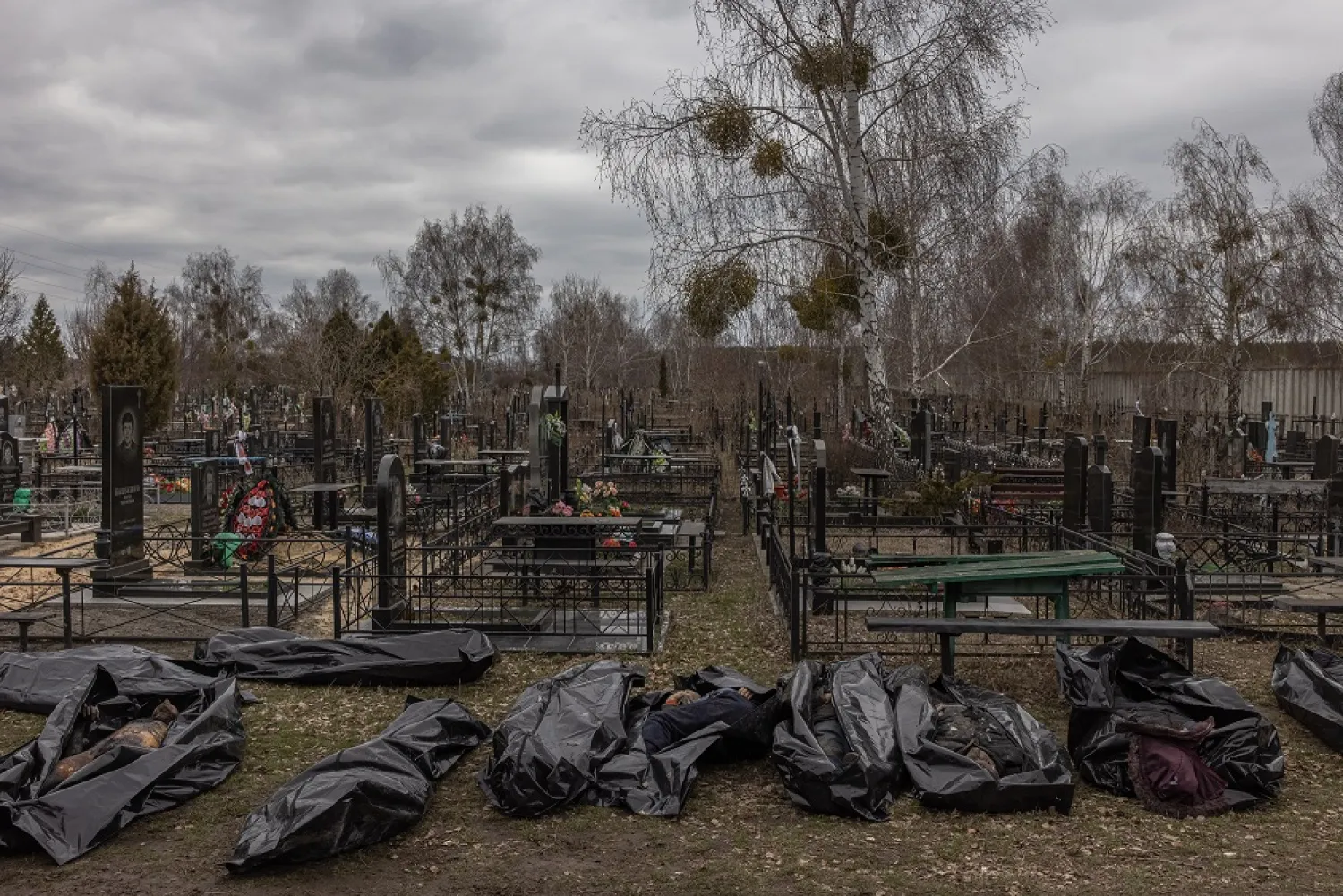 Bodies of killed people, which were brought to the cemetery, lay on the ground during the identification process by police officers and forensic personnel, in Bucha, northwest of Kyiv, Ukraine, 06 April 2022. (EPA)