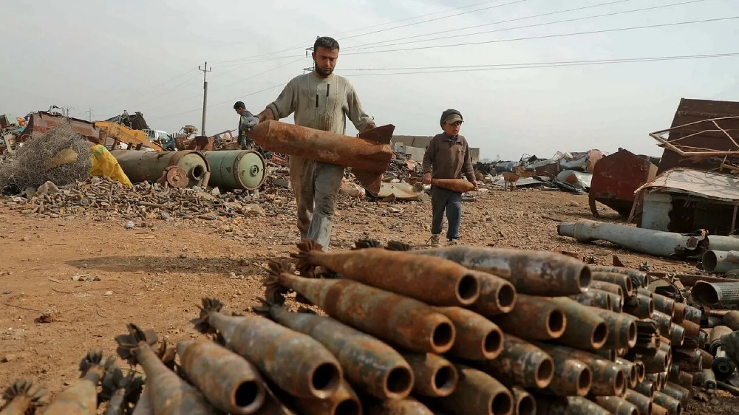 A Syrian family sorts unexploded ordnance at a metal scrapyard on the outskirts of Maaret Misrin town in the northwestern Idlib province, on March 10, 2021. (AFP)